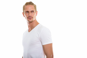 Studio shot of young handsome man thinking while looking back