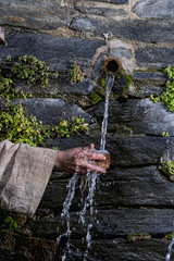 Hands of a beggar picking up water in a fountain