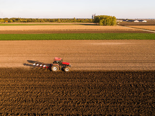 Obraz premium Aerial shot of a farmer plowing stubble field