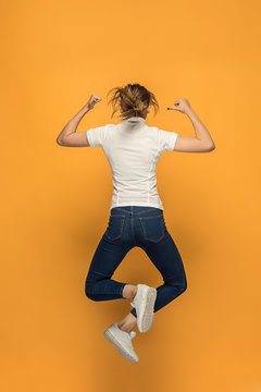 Closeup of young woman's body in empty white t-shirt on orange background. Mock up for disign concept