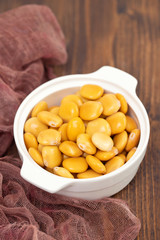 salted lupins in white bowl on brown wooden background