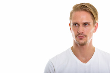 Studio shot of young handsome man thinking while looking at dist