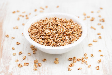 puffed spelt in white bowl on wooden background