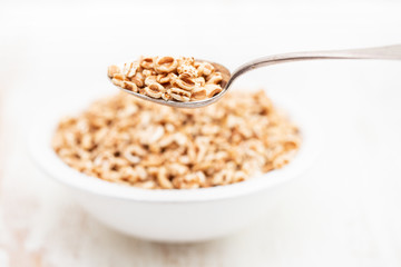 puffed spelt in white bowl on wooden background