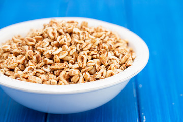 puffed spelt in white bowl on wooden background