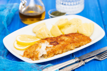 fried fillet of fish with boiled potato on white dish