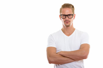Studio shot of young handsome man wearing eyeglasses with arms c