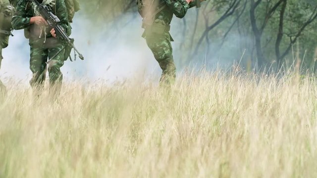 Soldiers aiming their assault rifle in jungle. Chinese soldiers in jungle walking toward camera in open grass land and aiming their weapon, special forces training. Ready to assault terrorist.