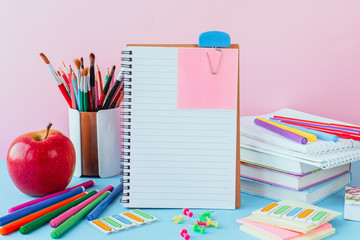 School and office supplies on classroom table in front of blue pink blackboard. View with copy space concept back to school