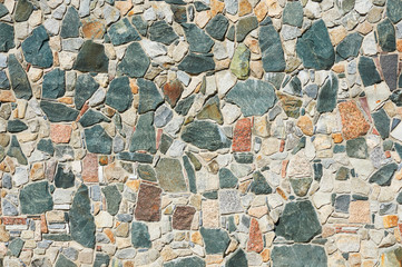The wall is made of multicolored stones. Abstract background.