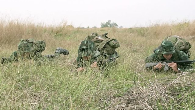 Slow motion of soldiers crawling on grass field. Three chinese special force soldiers crawling together on the grass land toward camera.