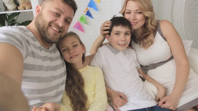 Cheerful family with two children and white rabbit taking selfies. Shooting first-person