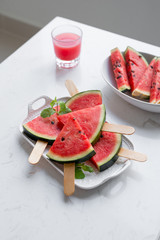 Fresh red smoothie in a glass with sliced pieces of watermelon on table.
