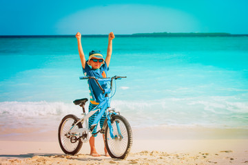 Fototapeta premium happy little boy riding bike on tropical beach