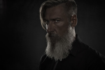 Porträt eines bösen bärtigen Mannes vor schwarzem Hintergrund © Cara-Foto