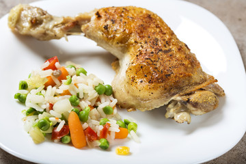 One fried chicken leg with boiled vegetables like rice, green peas and baby carrots