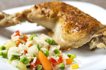 Boiled vegetables like rice, green peas and baby carrots and one fried chicken leg in background