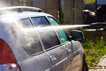 Washing a white dirty car with water jet from the washing machin