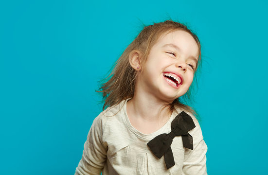 portrait of little girl laughing on blue isolated background