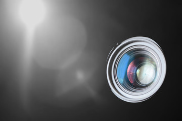 Photo camera lens macro against a black background with some light focus flare. Some reflections and empty copy space for Editor's text.