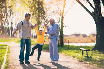 Two grandfather walking with the grandson in the park