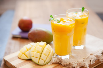 Fresh mango smoothie in glass with fruits on the wooden table