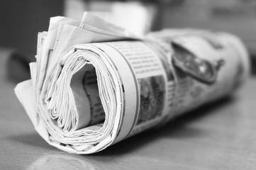 Rolled newspaper on table, selective focus  