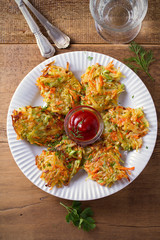 Potato Zucchini and Carrot Cakes. Vegetable fritters, latkes, draniki. Vegetable pancakes on white plate on wooden table. overhead, vertical