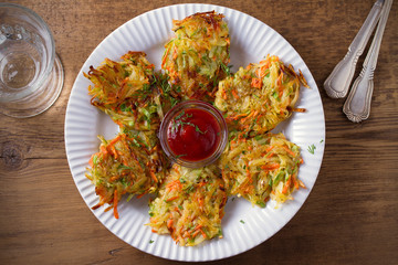 Potato Zucchini and Carrot Cakes. Vegetable fritters, latkes, draniki. Vegetable pancakes on white plate on wooden table. overhead, horizontal