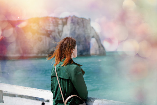 photo of beautiful young woman standing on the wonderful sea and cliffs background