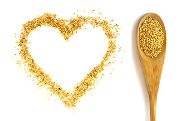 Wooden spoon with a long handle is filled with sesame seeds. Heart.  Isolated on white. The concept- kitchen, cooking, vegetarianism, healthy food.