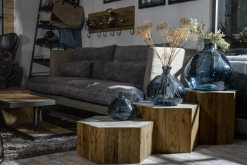 interior of modern retro styled living room with grey sofa and vases on wooden shelves