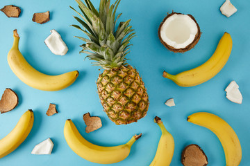flat lay with fresh pineapple, bananas and coconut pieces isolated on blue