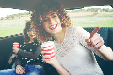 Dos amigas en un viaje en coche por la mañana con sus vasos de café 