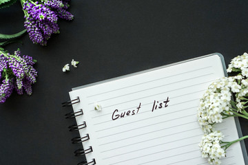Handwriting text Guest list on black background with violet small flowers