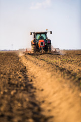 Farmer in tractor preparing land with seedbed cultivator as part of pre seeding activities in early spring season of agricultural works at farmlands.