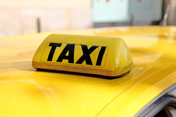 taxi in capital letters above the yellow car