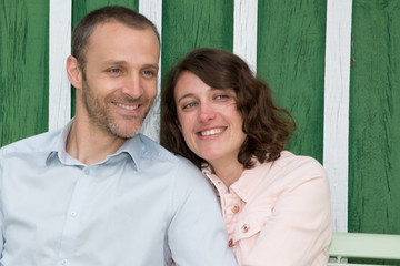 Couple in love sitting on bench front of wood hut in garden park