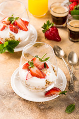 Healthy breakfast with oatmeal granola, strawberries and yogurt on light brown background. Copy space.