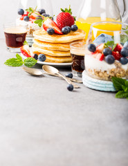 Breakfast background with fresh pancakes and berries on light gray concrete table. Healthy food...