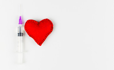 Heart and syringe  with red liquid on white background.