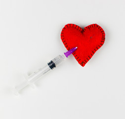 An injection of love in the heart. Stitched heart and syringe with red liquid on a white background.