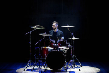 Fototapeta na wymiar Silhouette drummer on stage. Dark background, smoke spotlights
