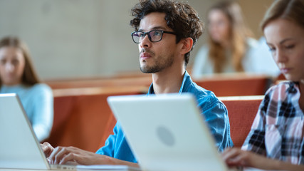 Handsome Hispanic Student Uses Laptop while Listening to a Lecture at the University. Multi Ethnic Group of Modern Bright Students.