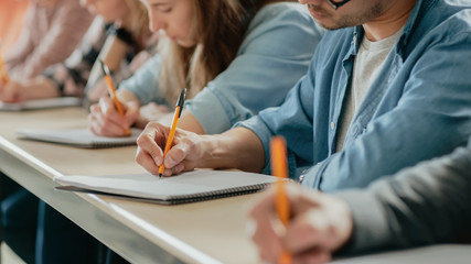 Row of Multi Ethnic Students in the Classroom Taking Exam/ Test/ Writing in Notebooks. Bright Young...