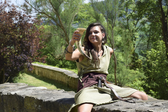 beautiful Celtic shieldmaid with drinking horn on the castle wall