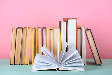 open book in front of row of books on table on pink