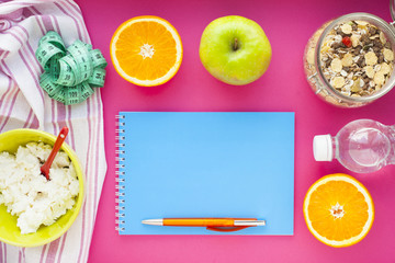 Fruits, curd, measuring tape, water and muesli on the pink background. Weight loss, diet controlled healthy food concept background. Top view, close up.