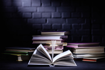 open book in front of stack of books on dark surface