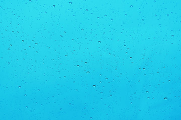 Raindrops on the glass, bright blue background.